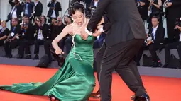 Aktris Korsel Moon So-ri kehilangan keseimbangan usai sepatu hak tingginya menginjak bagian bawah gaun yang panjang menjuntai di karpet merah pemutaran perdana film The Light Between Two Ocean di Venice Film Festival, Kamis (1/9). (FILIPPO MONTEFORTE/AFP)