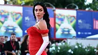 Tampilan menggoda gaun merah tersebut membuat Georgina Rodriguez memastikan semua mata tertuju padanya saat berpose di depan kamera. (GABRIEL BOUYS/AFP)