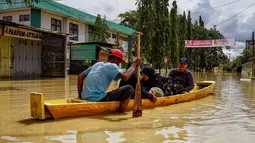 Warga menggunakan perahu untuk melewati jalan yang tergenang banjir setelah hujan lebat dan tanggul jebol, di Lhoksukon, Aceh Utara, 7 Oktober 2022. (AFP/Azwar Ipank)