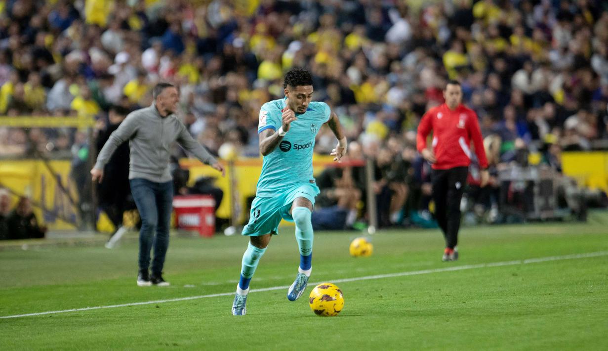 Pemain Barcelona, Raphinha, menggiring bola saat melawan Las Palmas pada laga La Liga 2023/2024 jornada 19 di Estadio de Gran Canaria, Jumat (5/1/2024). Berkat hasil ini, Barcelona berhak naik ke peringkat tiga klasemen dengan perolehan poin 41. Sementara itu, Las Palmas menduduki peringkat 10 dengan poin 25. (AFP/Desiree Martin)
