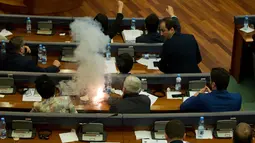 Seorang anggota parlemen Partai Vatevendosje menyalakan tabung gas air mata dalam sesi sidang di Pristina, Kosovo, Rabu (21/3). Aksi dilakukan demi mencegah pemungutan suara terkait masalah kesepatakan perbatasan dengan Montenegro (AP Photo/Visar Kryeziu)