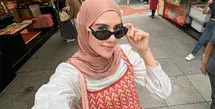 Syahnaz Sadiqah tampaknya konsisten berhijab. Gayanya saat ini dipuji makin cantik dan adem saat dilihat, termasuk potret yang satu ini. Ia tampil mengenakan set atasan tanpa lengan dan celana knitted bernuansa merah-oranye, dipadukan dengan oversized atasan putih sebagai inner, dan hijab cokelat yang serasi. [Foto: Instagram/syahnazs]