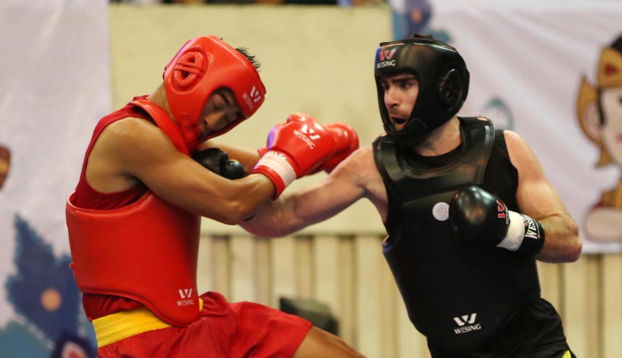 Atlet Wushu Asal China (kiri) menerima pukulan dari Atlet Turki pada Cabang Sanda Kejuaraan Dunia Wushu 2015 di Istora, Senayan, Jakarta,Rabu (18/11/2015). (Bola.com/Nicklas Hanoatubun)