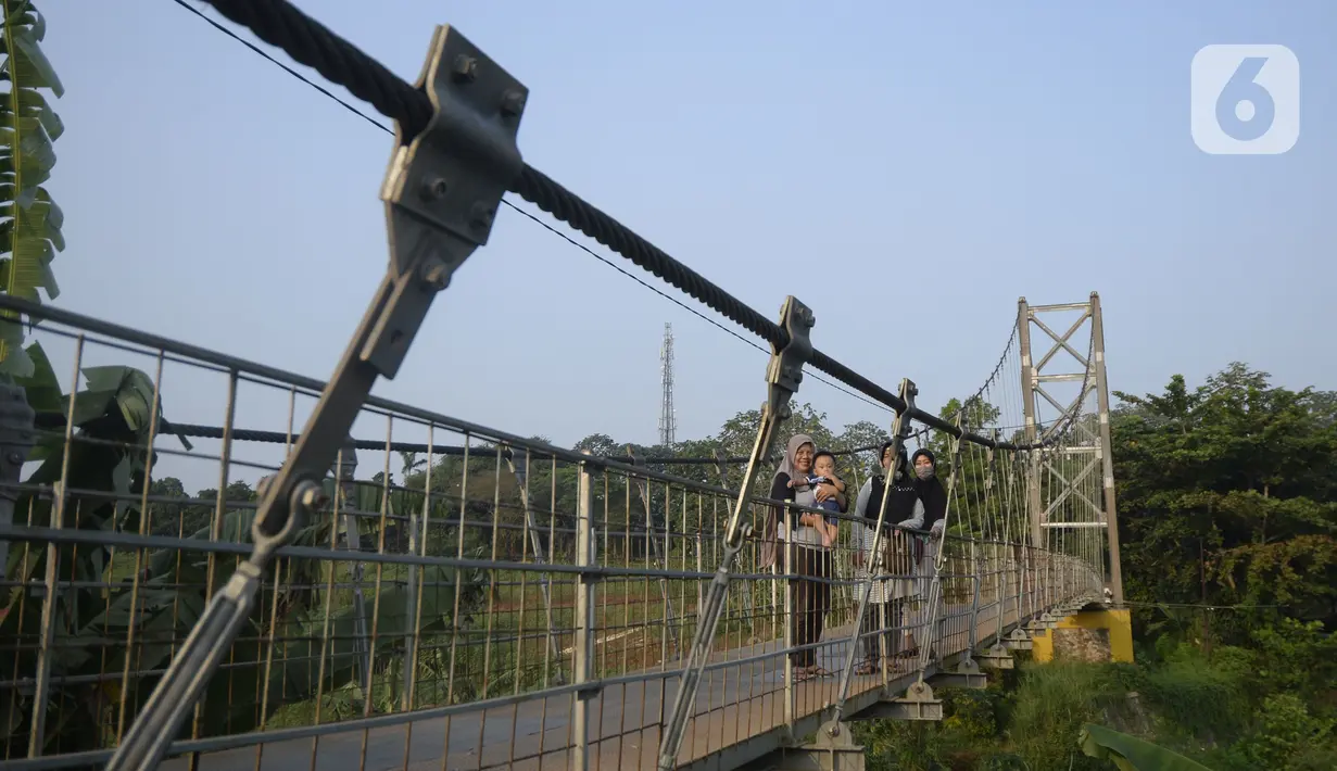Warga melihat-lihat pemandangan dari atas jembatan gantung di Kelurahan Curug, Bojongsari, Kota Depok, Jawa Barat, Senin (24/8/2020). Setiap sore, warga sekitar bermain di jembatan tersebut sambil menikmati matahari tenggelam. (merdeka.com/Dwi Narwoko)