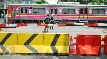 Warga mengambil gambar KRL yang melintasi perlintasan kereta api Stasiun Tebet, Jakarta, Kamis (7/4). Dishubtrans DKI melakukan uji coba penutupandan pengalihan arus lalu lintas di bawah flyover Tebet tepat depan Stasiun Tebet. (Liputan6.com/Yoppy Renato)