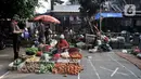 Pedagang berjualan dekat tanda ‘X‘ yang digunakan sebagai pembatas physical distancing di Pasar Perumnas Klender, Jakarta, Kamis (18/6/2020). Selain sistem ganjil genap kios, pengelola pasar menerapkan physical distancing antarlapak untuk mencegah penularan COVID-19. (merdeka.com/Iqbal S. Nugroho)