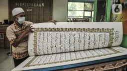 Petugas membaca sepenggal ayat dari Alquran raksasa koleksi Perpustakaan Jakarta Islamic Center (JIC), Jakarta Utara, Kamis (22/4/2021). Alquran tersebut berukuran 142 cm x 95 cm dan terdiri dari 604 halaman. (merdeka.com/Iqbal S Nugroho)