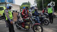 Petugas kepolisian lalu lintas memberhentikan pengendara motor saat Operasi Zebra Jaya 2020 di kawasan Cawang, Jakarta, Senin (26/10/2020). Operasi Zebra Jaya dilaksanakan pada 26 Oktober-8 November 2020 untuk menekan jumlah pelanggaran lalu lintas. (Liputan6.com/Faizal Fanani)