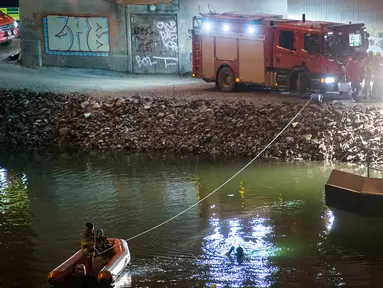 Regu penyelamat mencari korban kecelakaan mobil di kanal di bawah jembatan jalan raya E4 di Sodertalje, Swedia, Sabtu (13/2). Empat anggota band Viola Beach dari Inggris dan manajernya tewas dalam kecelakaan tersebut. (JOHAN NILSSON/TT NEWS AGENCY/AFP)