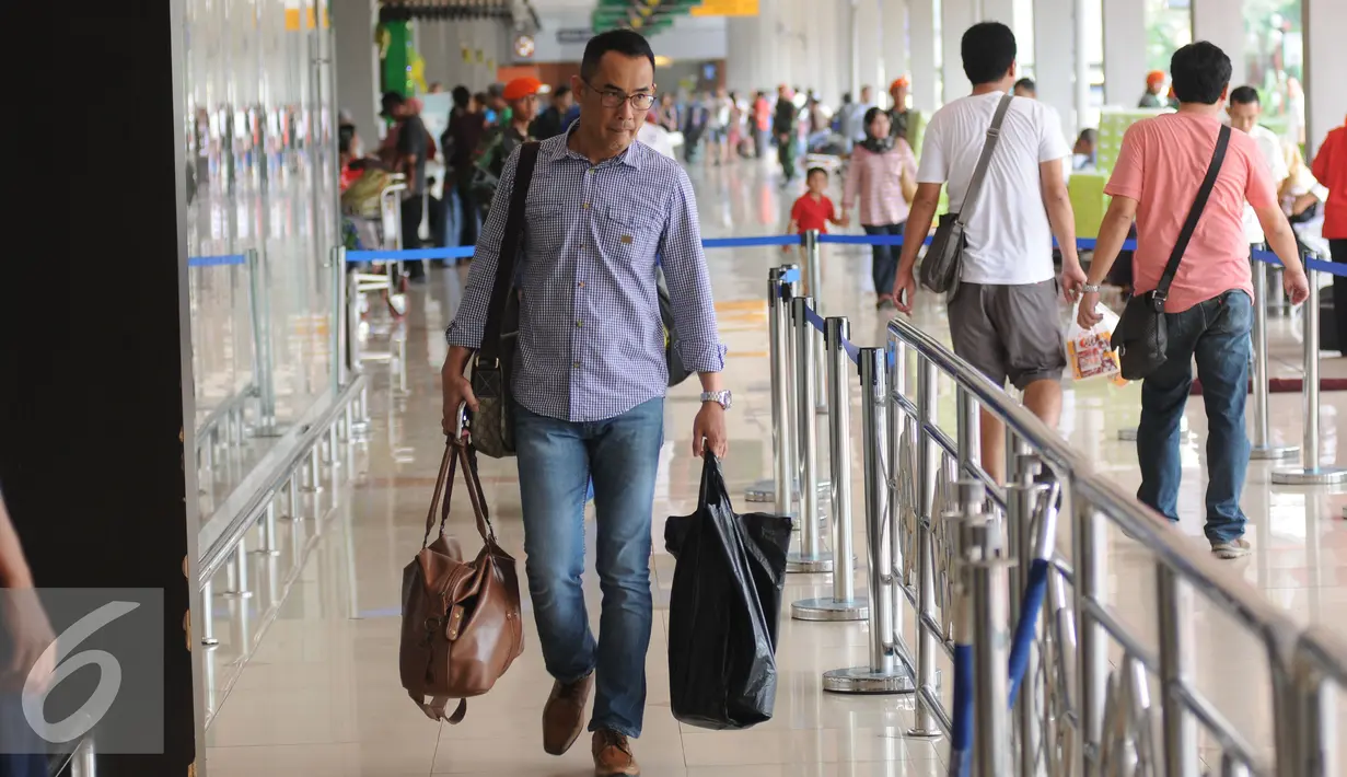 Seorang calon penumpang bersiap masuk ke dalam Bandara Halim Perdanakusuma Jakarta, Senin (4/7). H-2 jelang Idul Fitri 1437 H, ribuan calon penumpang diberangkatkan dari Bandara Halim Perdanakusuma. (Liputan6.com/Helmi Fithriansyah)