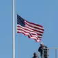 Petugas seusai menurunkan bendera setengah tiang di Gedung Putih, Washington DC, sebagai tanda berduka atas penembakan brutal klub gay Pulse di Kota Orlando, Florida, Amerika Serikat (AS), Minggu (12/6). (AFP PHOTO/Yuri GRIPAS)