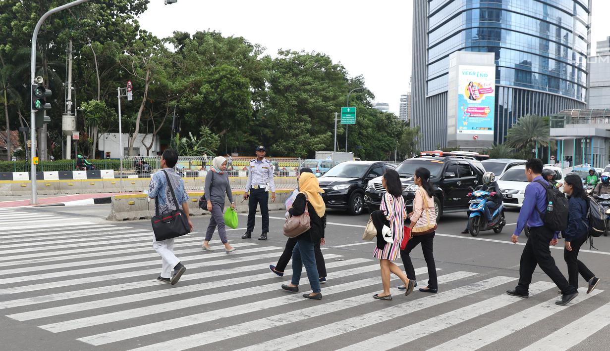 Petugas Dinas Perhubungan DKI Jakarta mengawasi warga yang menyebrang di kawasan Tosari, Jakarta, Jumat (14/12). Penggunaan pelican crossing di kawasan ini menggantikan fungsi JPO Tosari yang akan dibongkar. (Liputan6.com/Helmi Fithriansyah)