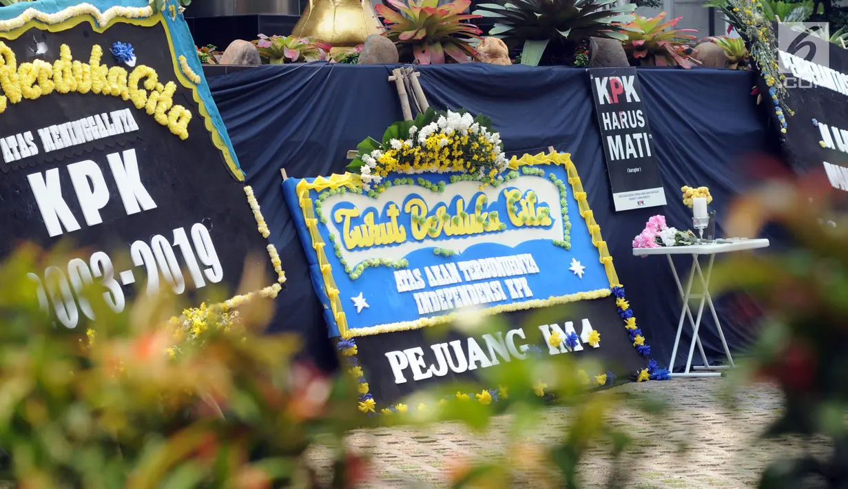 Sejumlah karangan bunga diletakkan dekat kain hitam besar yang menutupi logo KPK di Gedung Merah Putih, Jakarta, Senin (9/9/2019). Keberadaan kain hitam dan karangan bunga ini merupakan bentuk protes atas revisi Undang-undang KPK yang dinilai dapat melemahkan KPK. (merdeka.com/Dwi Narwoko)