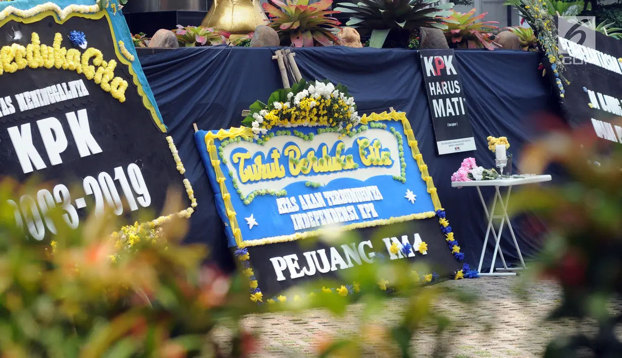 Sejumlah karangan bunga diletakkan dekat kain hitam besar yang menutupi logo KPK di Gedung Merah Putih, Jakarta, Senin (9/9/2019). Keberadaan kain hitam dan karangan bunga ini merupakan bentuk protes atas revisi Undang-undang KPK yang dinilai dapat melemahkan KPK. (merdeka.com/Dwi Narwoko)