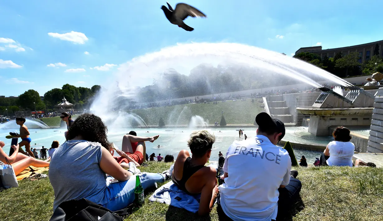 Warga berjemur di samping air mancur di Trocadero Esplanade, dekat Menara Eiffel, Paris (8/5). Tempat ini di desain oleh arsitek Roger-Henri Expert. (AFP Photo/Gerard Julien)