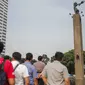 Aktivis lingkungan Green Peace turun usai membentangkan spanduk di Patung Selamat Datang, Bunderan HI, Jakarta, Rabu (23/10/2019). Dalam aksi yang telah berlangsung selama 13 jam tersebut, mereka diamankan oleh petugas kepolisian yang telah berjaga dibawah. (Liputan6.com/Faizal Fanani)