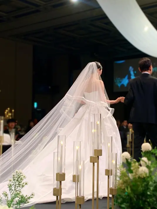 Dimulai dengan foto dirinya berjalan di altar mengenakan strapless gown warna putih, lengkap dengan veil-nya. [@yukyung_922]