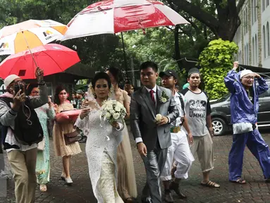 Sejumlah orang dari ormas islam memayungi sepasang mempelai yang akan melangsungkan pernikahan di Gereja Katedreal, Sabtu (11/2). (Liputan6.com/Herman Zakharia)