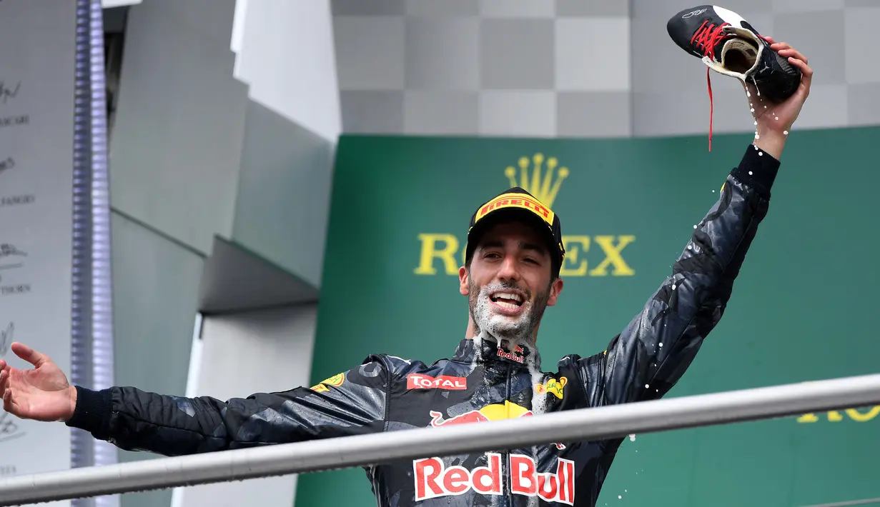 Pembalap Red Bull Daniel Ricciardo menunjukkan sepatu miliknya usai merayakan keberhasilan naik podium pada Grand Prix Formula 1 Jerman, Minggu (31/7). Ricciardo yang menjadi juara kedua meminum sampanye menggunakan sepatunya. (Patrik STOLLARZ / AFP)