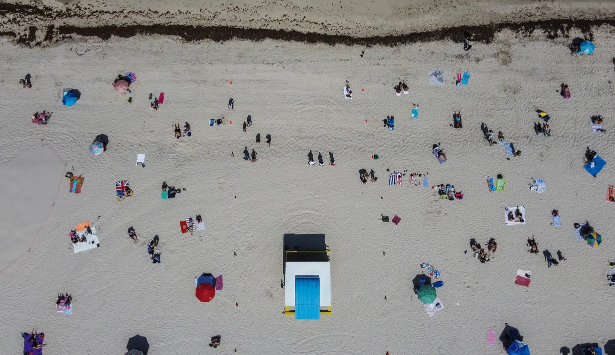Pandangan udara menunjukkan orang-orang berada di atas pasir Miami Beach di Florida, Rabu (10/6/2020). Pantai Miami dibuka hari ini untuk pertama kalinya setelah hampir tiga bulan ditutup guna menekan jumlah penyebaran corona Covid-19. (CHANDAN KHANNA / AFP)