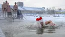 Seorang pria berpakaian seperti Ded Moroz (Santa Claus) berenang di air sedingin es selama hari yang membekukan di kota Omsk di Siberia, Rusia, Sabtu (26/12/2020). Suhu di Omsk turun hingga -32 derajat Celcius atau -25,6 derajat Fahrenheit. (AP Photo/Evgeniy Sofiychuk)