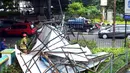 Kondisi papan reklame yang roboh saat sedang dipotong petugas pemadam kebakaran di Jalan Soepomo, Jakarta, Sabtu (28/5/2022). Hujan disertai angin kencang pada pagi tadi membuat papan reklame roboh sehingga membuat kemacetan arus lalu lintas di jalan tersebut. (merdeka.com/Imam Buhori)