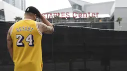 Gennesys Cabral, dari Los Angeles, mengenakan jersey Kobe Bryant di luar Staples Center, Los Angeles (26/1/2020). Selain Bryant, empat orang lainnya dalam helikopter itu juga dinyatakan meninggal dunia. (AP Photo/Chris Pizzello)