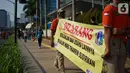 Spanduk larangan berjualan yang dibentangkan petugas Satpol PP di jalur Hari Bebas Kendaraan Bermotor atau Car Free Day, Jakarta, Minggu (3/11/2019). Pemprov DKI melarang PKL berjualan di sepanjang jalur Car Free Day yang selama ini memenuhi jalan serta trotoar. (Liputan6.com/Immanuel Antonius)