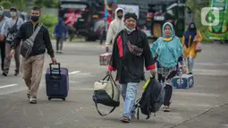 Peserta Mudik Aman Mudik Sehat Kementerian Perhubungan membawa barang bawaan mereka berjalan menuju bus tujuan kampung halamannya di Terminal Jatijajar, Depok, Jawa Barat, Kamis (28/4/2022). Sekitar 3.000 penumpang diberangkatkan dengan 106 bus yang telah disiapkan oleh Dirjen Darat Kementerian Perhubungan. (Liputan6.com/Faizal Fanani)