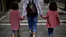 Keluarga berjalan-jalan di sepanjang jalan kota lama, di Pamplona, Spanyol utara (27/4/2020). Anak-anak di bawah 14 tahun diizinkan untuk berjalan-jalan dengan orang tua hingga satu jam dan dalam satu kilometer dari rumah, mengakhiri enam minggu pembatasaan. (AP Photo/Alvaro Barrientos)