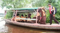 Anggota Polisi rutin membantu siswa menyebrangi sungai. Foto: (M Syukur/Liputan6.com)