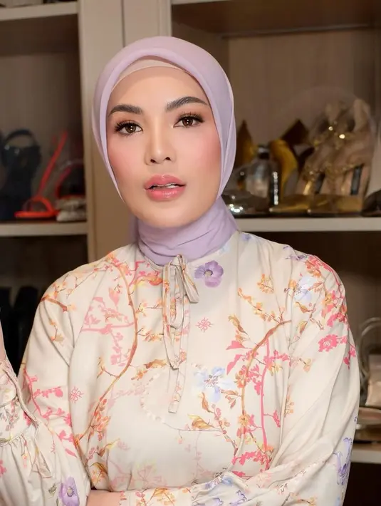 Nindy tampil dengan outfit bernuansa pastel, mengenakan kerudung ungu muda dipadukan busana dengan motif floral.  [@nindyayunda]