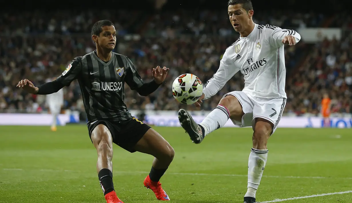 Cristiano Ronaldo coba mengelabui pemain Malaga Roberto Rosales dalam pertandingan yang berakhir dengan skor 3-1, Minggu (19/4/2015) dinihari WIB. (AP Photo/Andres Kudacki)