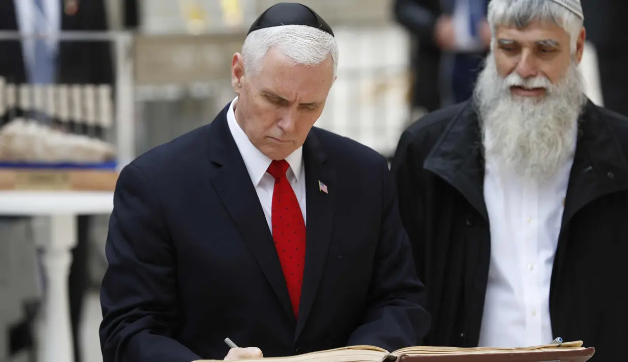 Wakil Presiden AS Mike Pence (kiri) menandatangani buku tamu saat berkunjung ke Tembok Barat Yerusalem (23/1). Mike Pence berjanji untuk memindahkan kedutaan ke kota yang disengketakan tersebut pada akhir tahun 2019. (AFP Photo/Thomas Coex)