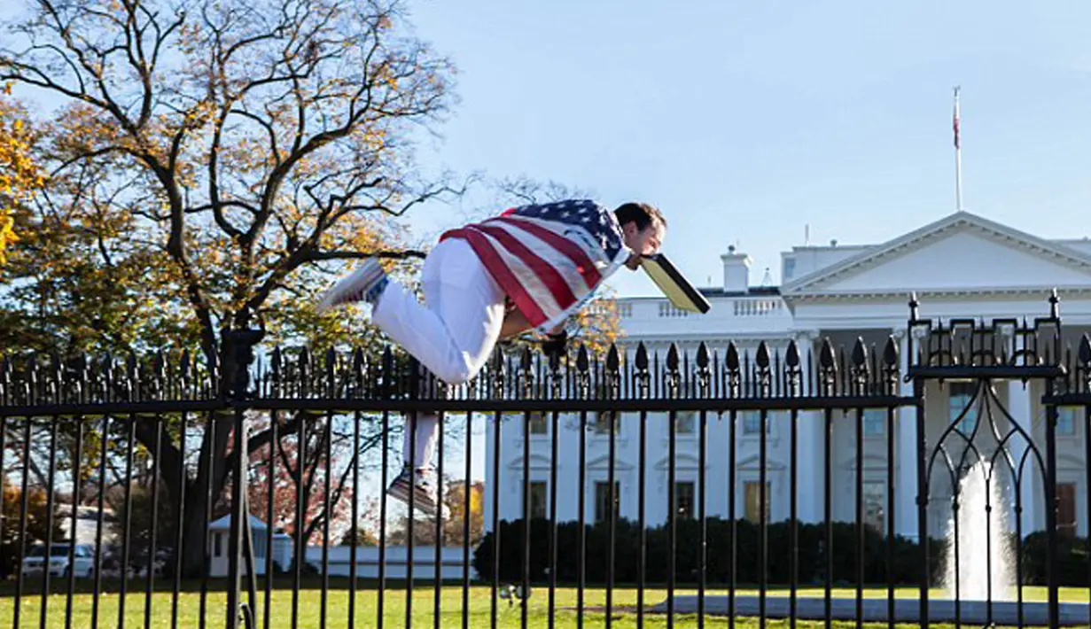 Seorang pria dengan membawa amplop dimulutnya berusaha menerobos pagar Gedung Putih di Washington, Kamis (26/11). Insiden itu terjadi pada saat Presiden AS Barack Obama sedang berada di dalam Gedung Putih merayakan hari Thanksgiving. (dailymail.co.uk)