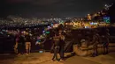 Dua tentara berjaga-jaga ketika orang-orang menikmati malam pada Hari Lilin Kecil di Medellin, Kolombia (7/12). Hari Lilin Kecil ini menandai awal musim Natal. (AFP Photo/Joaquin Sarmiento)