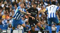Gelandang Man City, Rodri, berebut bola dengan bek Brighton, Lewis Dunk, dalam laga Premier League di AMEX Stadium, Minggu (31/8/2025). (JUSTIN TALLIS / AFP)