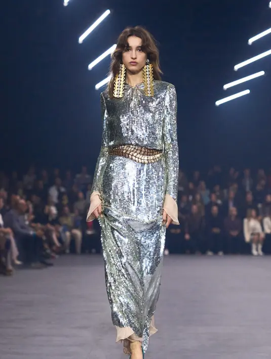 Gaun transparan bertabur payet emas dan perak memantulkan cahaya seolah-olah ratusan kunang-kunang beterbangan di udara. Ada juga gaun gaya flapper yang seluruh permukaannya diselimuti sequin krom, sementara pinggangnya disulam dengan motif kunang-kunang berkilau.  [Dok/Valentino].
