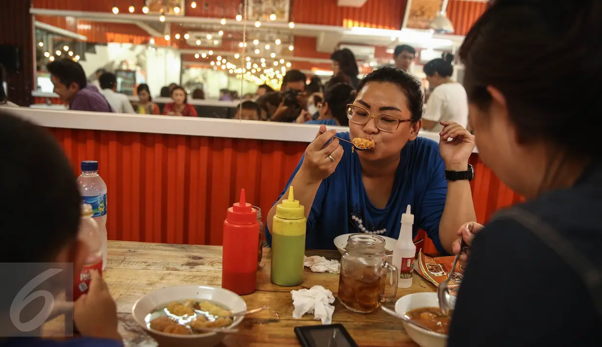 Pelanggan sedang menikmati salah satu menu di Warung Bakso Djingkrak Sunter di Jakarta, Kamis (28/4). Warung ini sempat menjadi pembicaraan di dunia maya karena pemiliknya ikut melayani para konsumen dengan pakaian seksi. (Liputan6.com/Faizal Fanani)