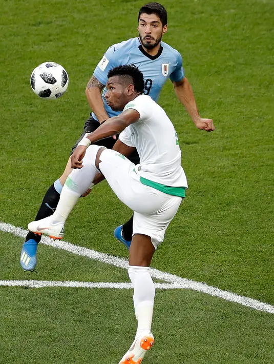 Pemain Arab Saudi, Ali Albulayhi berebut bola dengan penyerang Uruguay, Luis Suarez pada pertandingan kedua Grup A Piala Dunia 2018 di Rostov Arena, Rabu (20/6). Uruguay mengalahkan Arab Saudi 1-0 berkat gol Suarez di babak pertama. (AP/Themba Hadebe)