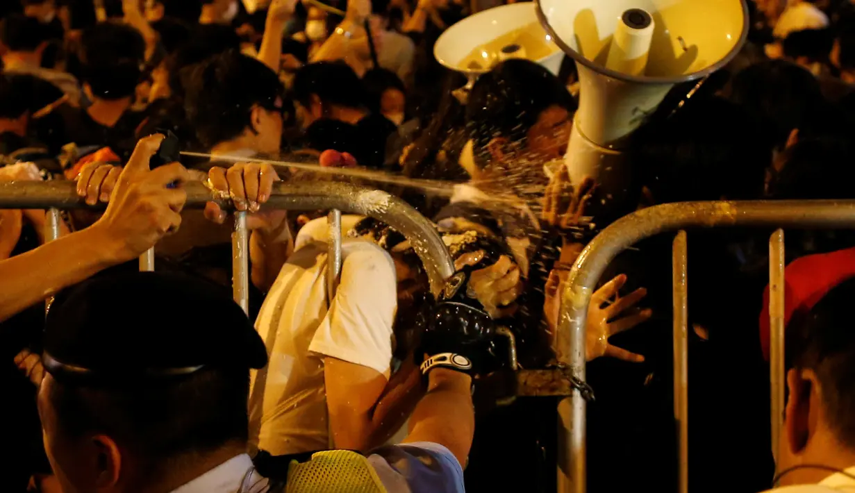 Pengunjuk rasa disemprot cairan merica oleh petugas saat demonstrasi yang berujung kericuhan di Hong Kong, Minggu (6/10). Kericuhan terjadi setelah massa terlibat deadlock selama delapan jam dengan aparat keamanan yang menjaga lokasi. (REUTERS/Tyrone Siu)
