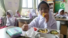 Seorang siswi sekolah dasar sedang menikmati menu makan bergizi gratis di Sekolah Dasar Negeri 01&02, Susukan, Jakarta, Senin (6/1/2025). (Liputan6.com/Herman Zakharia)