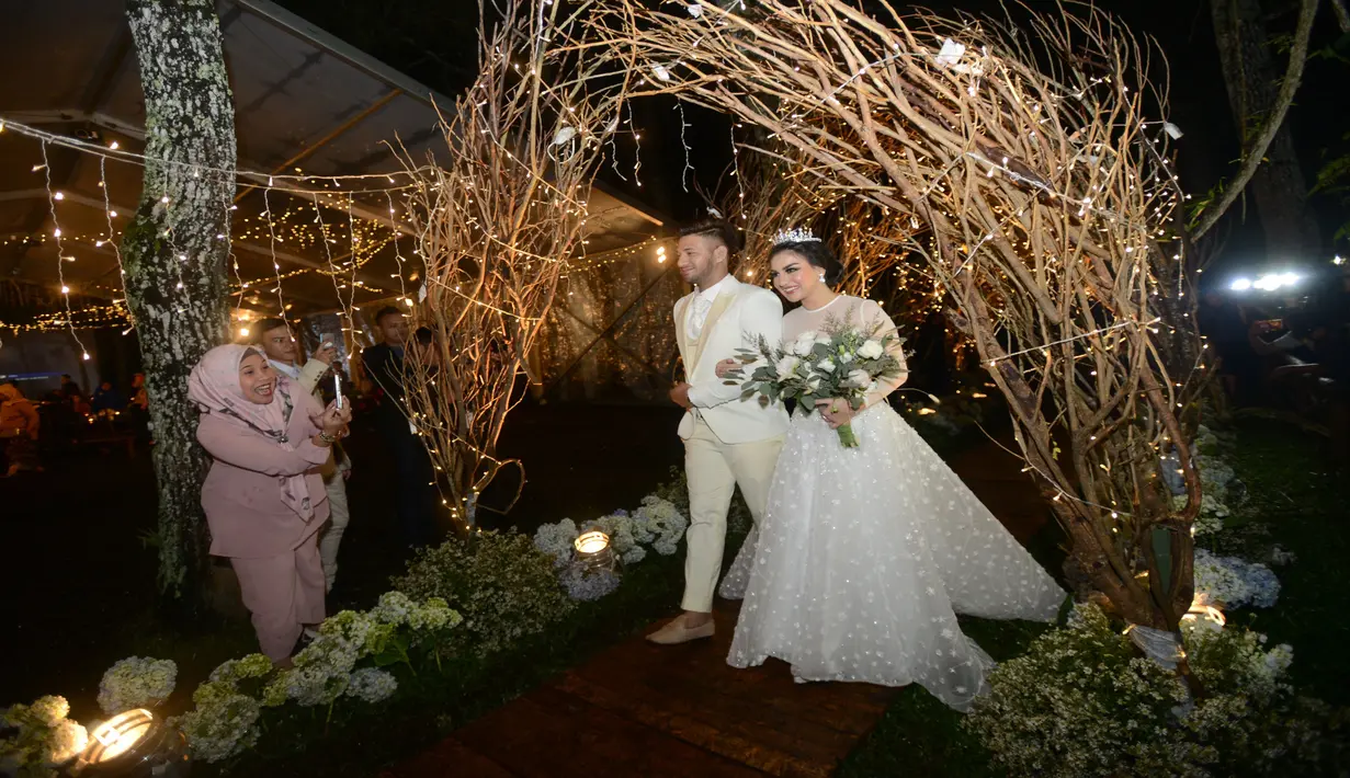Acara resepsi keduanya masih digelar di tempat yang sama seperti saat akad nikah. Untuk resepsi, keduanya memilih konsep peri hutan. Dalam resepsi pernikahan yang di gelar di alam terbuka tersebut, keduanya kompak menggunakan pakaian berwarna putih. (Kapanlagi.com/Bayu Herdianto)
