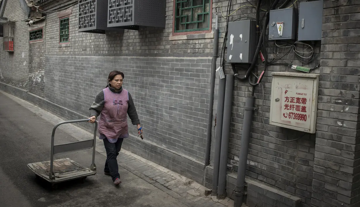Seorang pekerja restoran menarik troli di sebuah jalan di daerah hutong di Beijing (26/2). Istilah "hutong", terdahulunya bermakna "perigi air". (AFP Photo/Nicolas Asfouri)