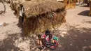 Nybol Madut duduk bersama anak-anaknya di tempat penampungan di Sudan Selatan (22/11). Mereka menderita krisis air bersih dan kelaparan karena minimnya persediaan pangan. (AFP Photo/Albert Gonzalez Farran)