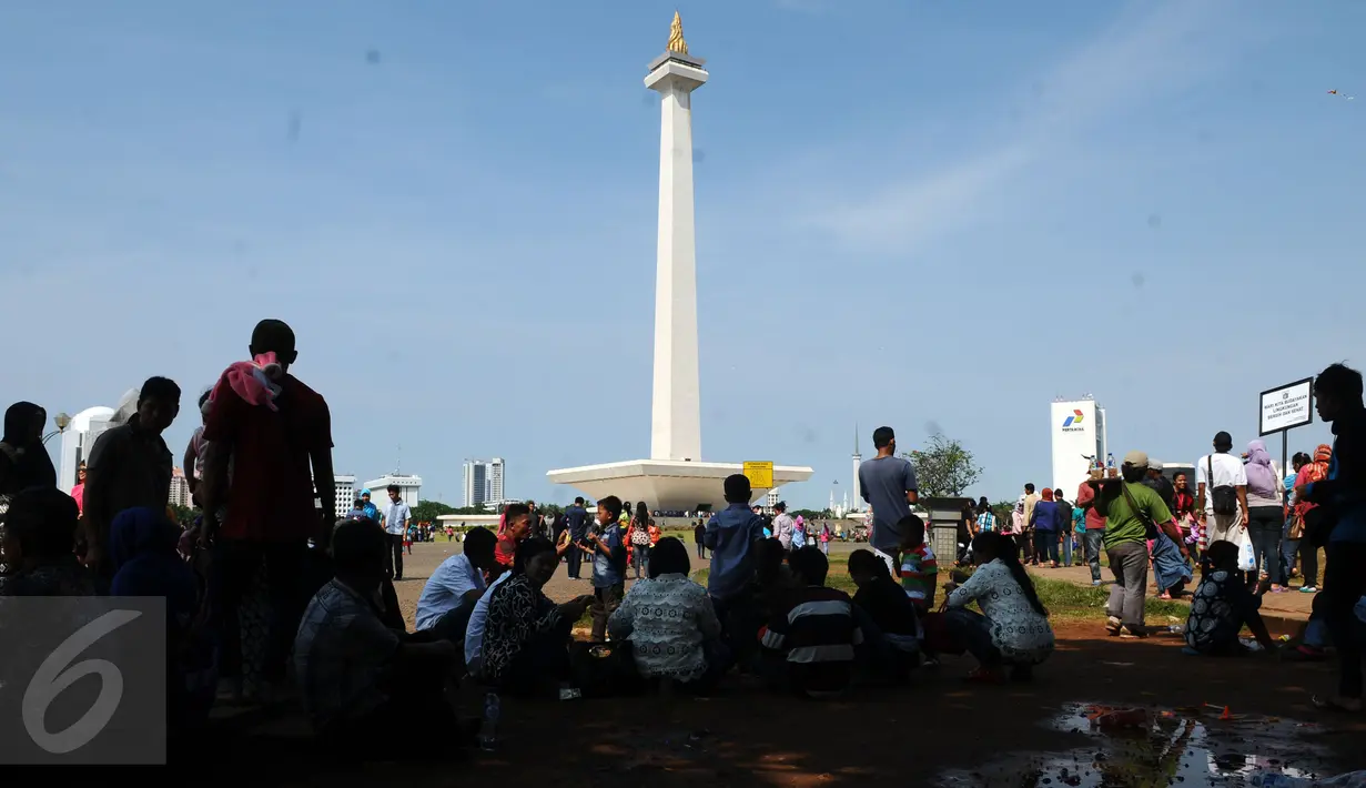 Sejumlah pengunjung beristirahat di bawah pohon yang ada di sekitar areal Monumen Nasional, Jakarta, Jumat (1/1/2016). Hari libur tahun baru 2016 dimanfaatkan ribuan warga untuk berwisata di kawasan Monumen Nasional. (Liputan6.com/Helmi Fithriansyah)