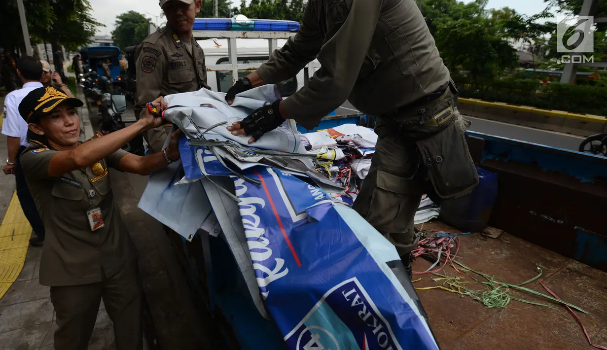 Petugas Satpol PP menertibkan APK Pemilu 2019 di Kawasan Jalan Pemuda, Jakarta, Rabu (13/3). APK Pemilu 2019 yang terpasang pada JPO dibersihkan hal tersebut mengganggu dan melanggar aturan pemasangan dari komisi Pemilihan umum. (merdeka.com/Imam Buhori)