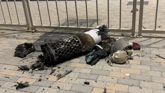 Sisa-sisa rudal Iran yang dicegat di atas Qatar, terlihat tergeletak di trotoar dekat pagar bangunan di lokasi pada Senin (23/6/2025) (Dok. AFP).