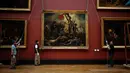 Pekerja galeri memindahkan lukisan "Liberty Leading the People" karya Delacroix (1798-1863) dari dinding Museum Louvre menjelang pekerjaan restorasi yang dijadwalkan berlangsung hingga musim semi 2024 di Paris, 20 September 2023. (Dimitar DILKOFF / AFP)