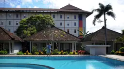 Seorang pekerja membersihkan kolam renang sebuah hotel saat Pemberlakuan Pembatasan Kegiatan Masyarakat (PPKM) Level 3 di Kuta, Badung, Bali, Jumat (23/7/2021). PPKM Level 3 di Bali berlaku hingga 25 Juli mendatang. (SONNY TUMBELAKA/AFP)